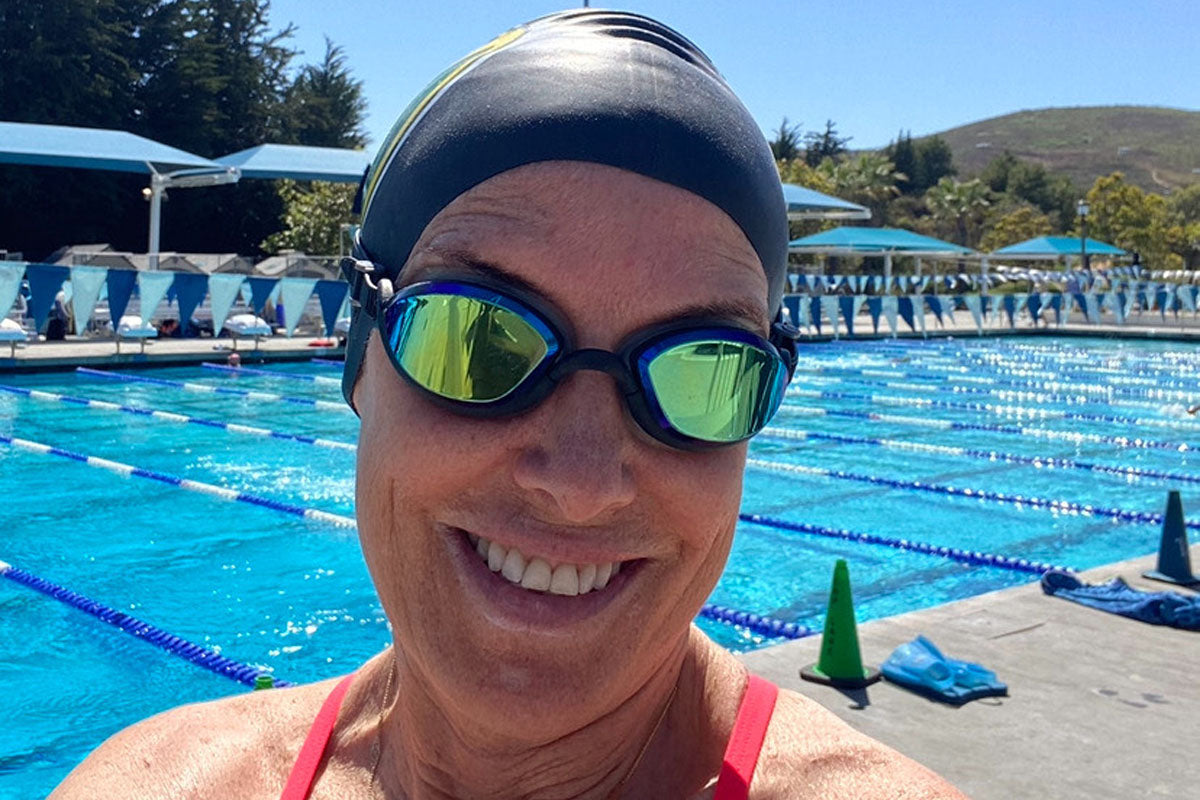 A woman at a pool wearing black, tinted Basilisks from Snake & Pig