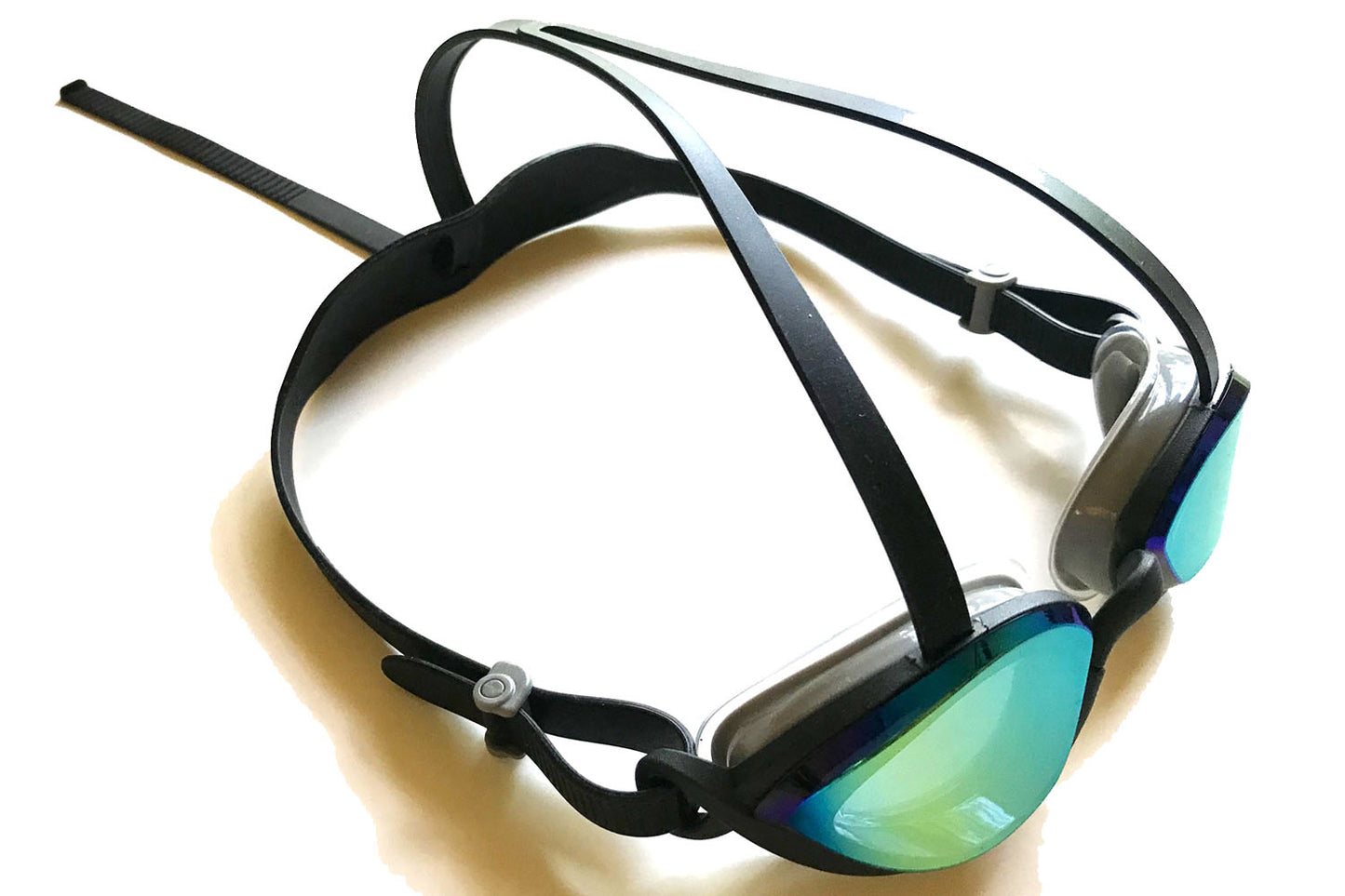 A pair of top anchor goggles with a dark tint, black side and top straps, and black frames on a white surface.