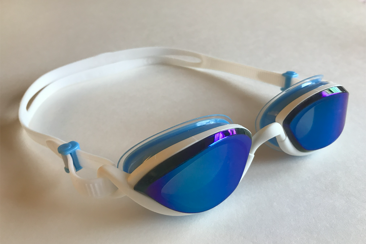 Smoke tinted goggles that appear blue tinted from the outside sitting diagonally on a white surface