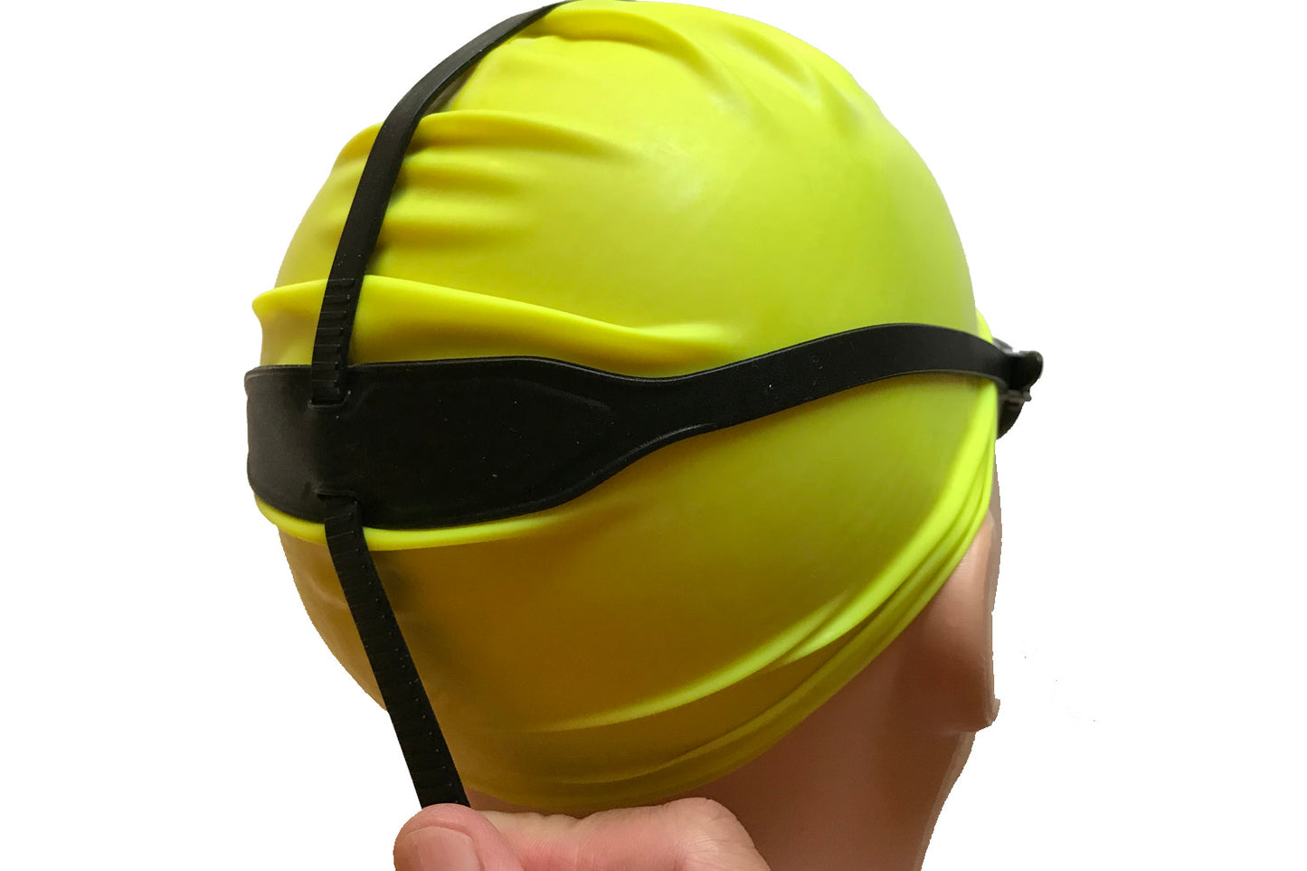 The back of a pair of top anchor goggles is shown on a dummy head. The top strap threads through a wide area of the side strap at the back, and fingers grip the bottom of the top strap to adjust it
