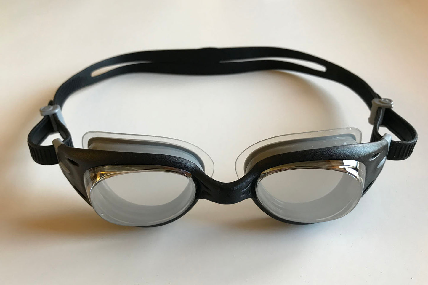 Junior Basilsk - black clear swimming goggles have a black frame and strap, and a metallized finish on the lenses