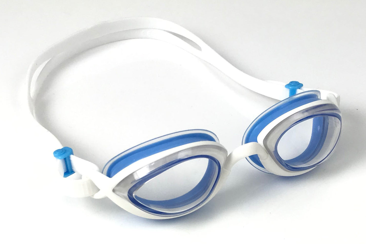 Clear Snake & PIg goggles with blue gaskets sit diagonally on a white surface
