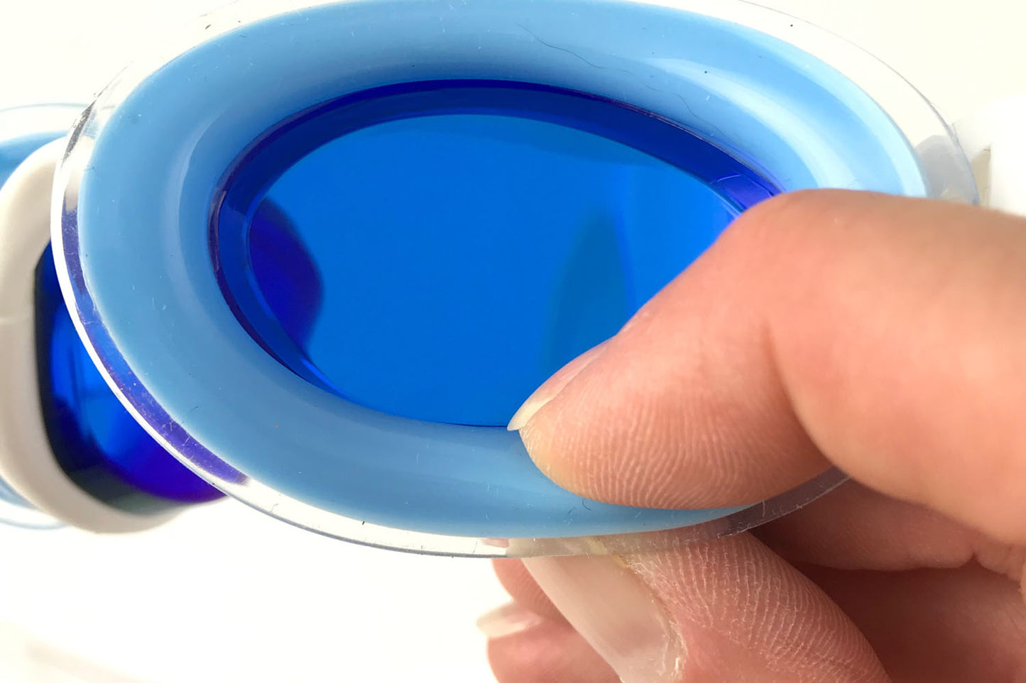 Fingers squish the air filled gasket of a pair of Snake & Pig goggles with blue lenses