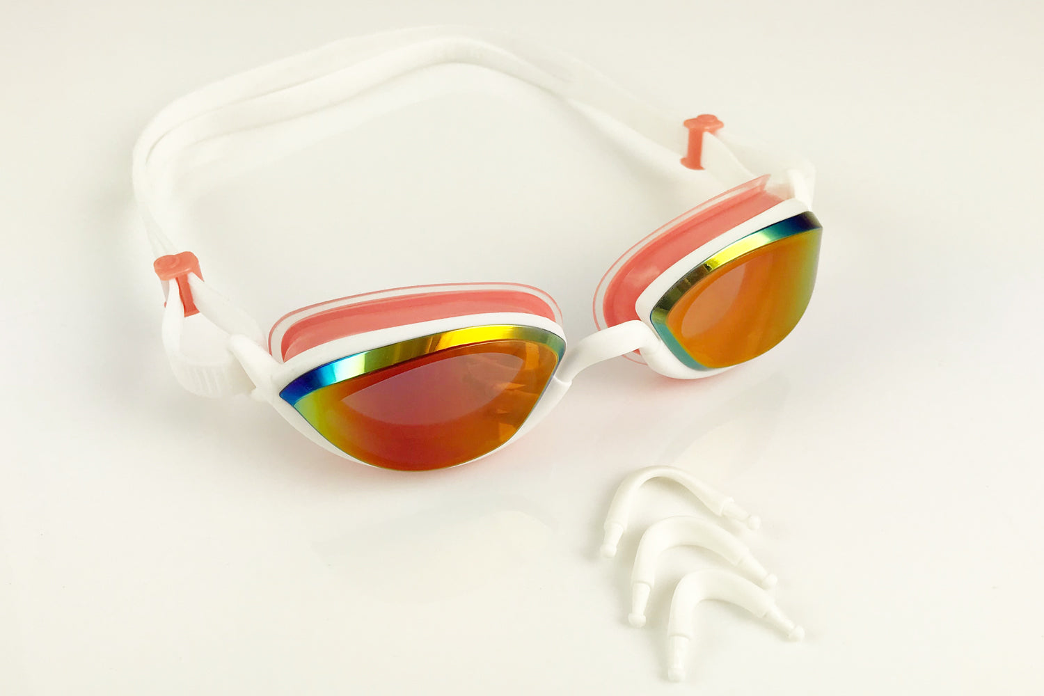 Pink Snake & Pig goggles on a white surface with the three sizes of the nosepieces in front