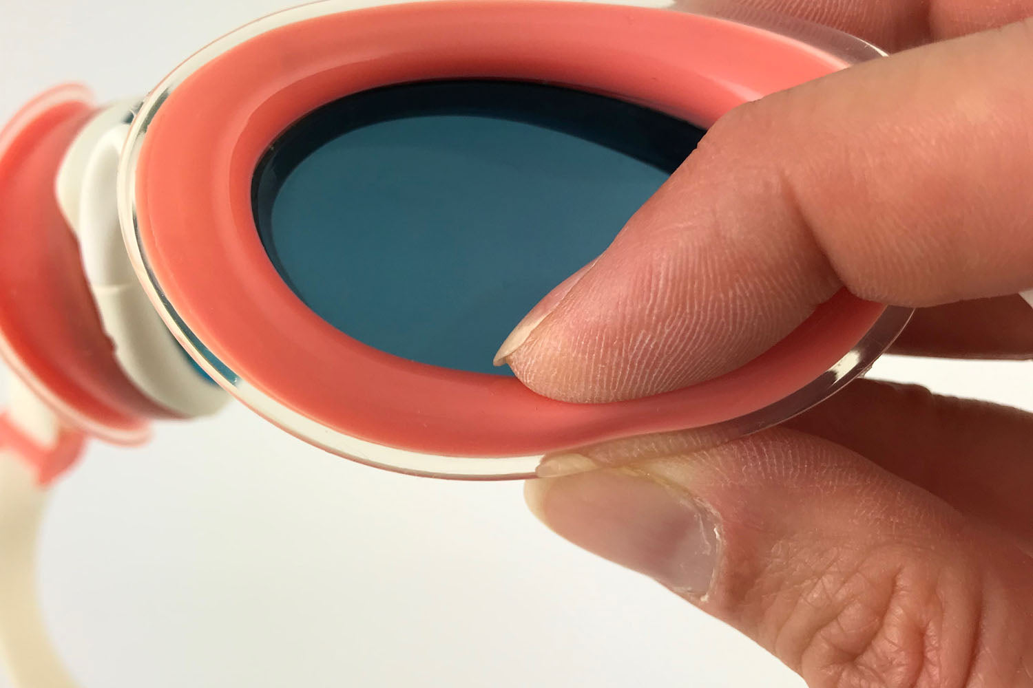 Fingers squishing the air cushion gasket of a pair of pink Snake & Pig goggles