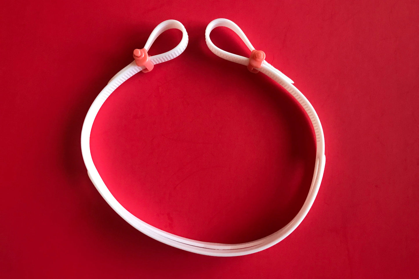 Snake & Pig goggles replacement strap - white strap with two pink buckles on a red background