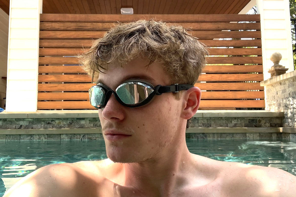 Young man wearing black clear Basilisk goggles in a backyard pool