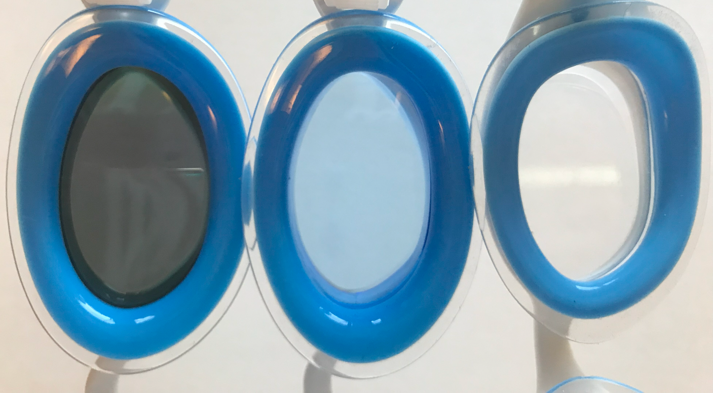 Comparison of the tints of three kinds of blue Basilisk goggles from L to R: blue, tinted showing a smoke tint from the inside; light blue lens; clear.